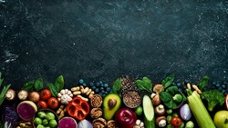 Healthy food banner. Set of fruits, vegetables, nuts, mushrooms and berries. On a black stone background. Top view. Copy space.