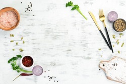 White kitchen background. Kitchen board, vegetables and spices on a white wooden background. Top view.