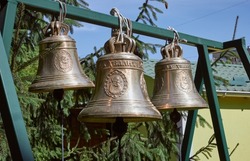 Three large metal bells. Church bells are hanging. The inscription on the bell - хвалит - praise.
