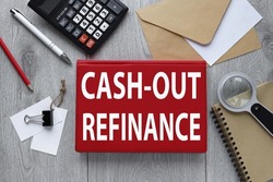 CASH-OUT REFINANCE red notepad on wood background with envelope and calculator