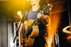The singer plays an acoustic guitar and sings at a concert
