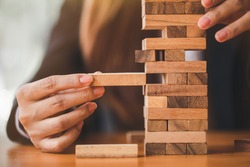 Woman's hand stacking wooden blocks  on a tower,. Business Planning,risk, strategy,development and Alternative risk concept.