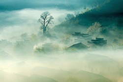 China Old City Town Anhui Landscape. Ancient Traditional Chinese Architecture Houses in Fog View. Peaceful Green Trees and Small Rural Village. Rustic Background Image.
