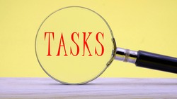 TASKS text on a yellow background through a magnifying glass