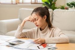 Financial owe asian young woman, girl sitting suffer, stressed and confused by calculate expense from invoice or bill, have no money to pay, mortgage or loan. Debt, bankruptcy or bankruptcy concept.