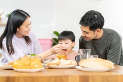 Happy refreshment family breakfast in morning, asian young parent father, mother and little cute boy, child having meal in kitchen eating together at home. Cheerful, enjoy cooking people.