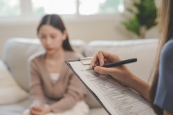Psychology, depression. Sad, suffering asian young woman consulting with psychologist, psychiatrist while patient counseling mental with doctor woman taking notes at clinic. Encouraging, therapy.