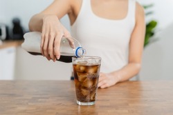 Thirsty, asian young woman, girl holding,  pouring cold cola soft drink soda, sparkling water with ice sweet sugar from bottle into glass in her hand. Health care, healthy diet lifestyle concept.