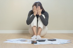 Financial owe asian woman, sitting on floor, cover face with hands, stressed by calculate expense from invoice or bill, have no money to pay, mortgage or loan. Debt, bankruptcy or bankrupt concept.