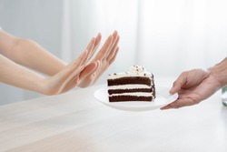 Diet, Dieting unhealthy asian young woman hand in push out, rejecting eat chocolate cake or sweet taste, fighting to keep it from getting fat when person bring to me. Healthy, nutrition of weight loss