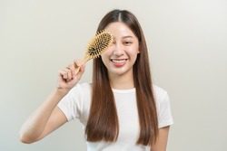 Health hair care, smile beautiful asian woman hand in holding hairbrush and brushing, combing her long straight hair in the morning routine after salon treatment, hairstyle. Isolated on background.