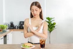 Diet, Dieting hand of asian young woman deny, avoid hamburger, junk or fast food and sparkling water, soft drink, eat food for good healthy, health when hungry. Temptation of weight loss people.