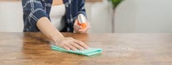 Hand of asian young woman, girl cleaning wood table, use rubs dust, rags ,spray bottle in kitchen at home. Household hygiene cleanup, cleaner people, equipment or tool for cleaning.