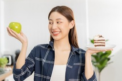 Diet asian young woman lose weight for health choosing to eat green apple, fruit do not choose eat chocolate cake, bakery because will make fat when hungry, female weight loss person, temptation food