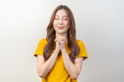 Hopeful make wish or please, calm asian young woman belief, hand in prayer. Christian praying to God for ask, request with closed eyes dreaming for help, thank you Meditation isolated on background.