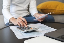 Deduction planning concept. Asian young woman hand using calculator to calculating balance prepare tax reduction income, cost budget expenses for pay money form personal Individual Income Tax Return.