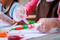 Asian siblings child girl enjoy making tie dye cloth together at home. Art and craft DIY for children concept.