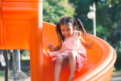 Cute asian child girl having fun to play slider in the playground in summer time