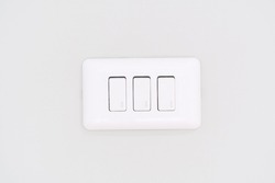 three white lighting switchs on white concrete wall.