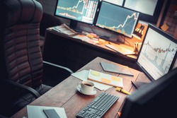 Stock trader workplace with financial market graphs on computer monitors