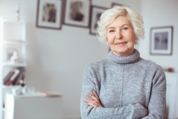 Portrait of handsome grandmother in gray sweater, crossed hands