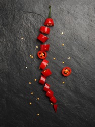 Red hot chilli pepper on dark black rough slate stone surface background