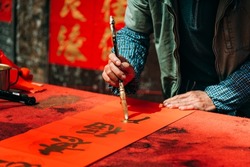 People write Spring Festival couplets with brushes with gold lacquer to celebrate Chinese New Year. Chinese characters
