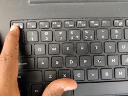 Finger pressing a Esc (Escape) button on the laptop keyboard. Selective focus