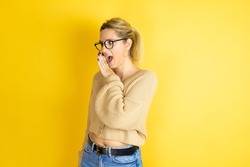 Young beautiful woman wearing casual sweater over isolated yellow background hand on mouth telling secret rumor, whispering malicious talk conversation