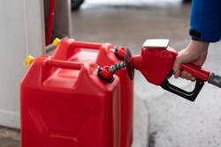 A man fills jerry cans at a gas station, Quebec, Canada
