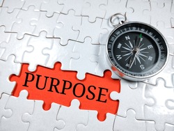 Selective focus.Word PURPOSE with compass on jigsaw puzzle and red background.Business concept.