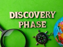 Selective focus.Top view compass,magnifying glass,earth globe and wooden word with text DISCOVERY PHASE on green background.