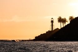 Sunset at the new Point Loma lighthouse in San Diego, California with waves and palm trees.