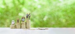 Saving for retirement and pension fund concept : Senior retired couple, vintage clock, US dollar money bag, deposit saving jar on steps of rising coins, depicts long-term investment for aging society