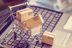Online shopping  e-commerce and customer experience concept : Boxes with shopping cart on a laptop computer keyboard, depicts consumers  buyers buy or purchase goods and service from home or office