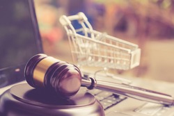E-commerce law, rules and regulations concept : Wooden judge gavel and shopping cart on a laptop, depicts good practice vendor must do for consumer e.g provide clear data, order cancellation, refund