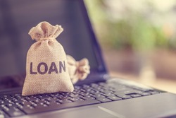 Online personal loan, financial concept : Loan bags on a laptop, depicting peer-to-peer lending, the practice of lending money to individual or business via online service among lenders and borrowers