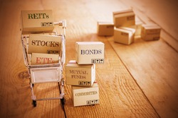 Vintage color style : Cartons of financial investment products in a shopping cart i.e REITs, stocks, ETFs, bonds, mutual funds, commodities. A concept of portfolio management with risk diversification