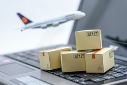 Mini cardboard boxes on a laptop with a plane flies behind. For several purposes or ideas about transportation, international freight, global shipping, overseas trade, regional  / local forwarding. 
