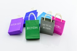 Colorful paper shopping bag of many types of financial investment products i.e. stocks, bonds, mutual funds, ETFs, REITs, commodities. An idea about diversifying assets in a portfolio to minimize risk