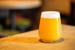 Hazy NEIPA New England IPA pale ale beer, on wood surface, rich frothy foam head with copy space
