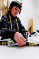 Dressmaker woman measuring the garments to design them.