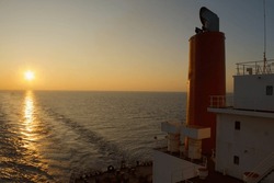 View of the stern of a merchant ship at sea in the evening during sunset