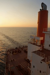 View of the stern of a merchant ship at sea in the evening during sunset