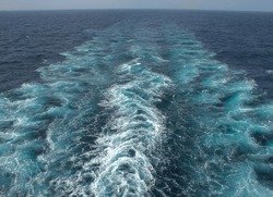 View from the stern of a merchant ship at sea with a clear view of waves from propeller wash