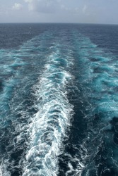 View from the stern of a merchant ship at sea with a clear view of waves from propeller wash