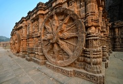 Wheels and pillars of Sun temple chariot hand carved in red sandstone, Konark, India.
