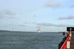 A view on the Port of Rotterdam at  New Waterway (Nieuwe Waterweg) ship canal in North Sea at Hoek Van Holland, The Netherlands. MS Iona Southampton and wind turbines in the distance. Space for copy. 