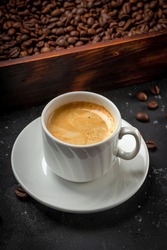 Cup of black coffee and roasted coffee beans in a wooden box vertical photo. High quality photo