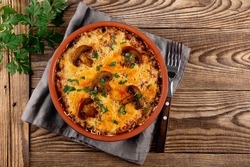 Julienne with potatoes and mushrooms in a baking dish on a wooden background, top view copy space for text. Traditional French dish